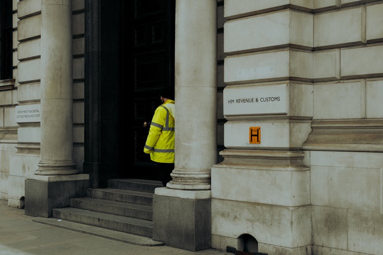 HMRC and Creditors 2 A guard in yellow jacket at the entrance of HM Revenue & Customs building in the UK.